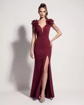 Modella con abito lungo bordeaux con fiore decorativo sulle spalle e spacco sulla gonna