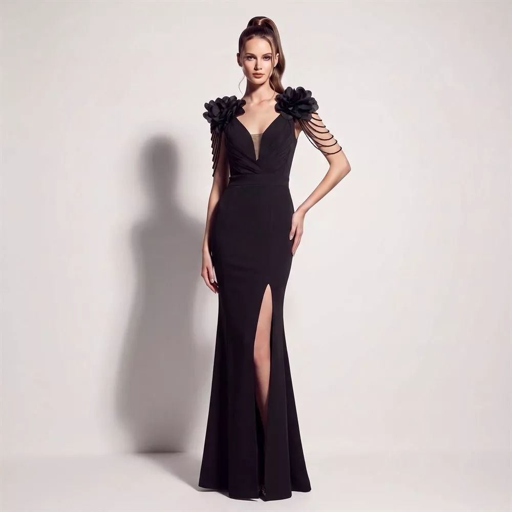 Modella con abito lungo nero con fiore e catene alle spalle, scollo a V profondo