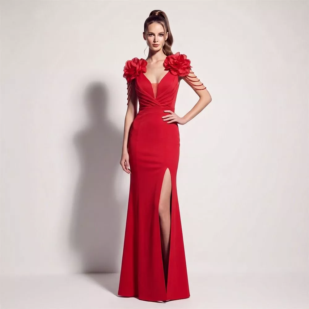 Modella con abito lungo rosso con decorazioni floreali sulle spalle e gonna aderente con spacco