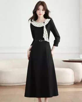 Modella indossa abito nero lungo con maniche lunghe e finta sciarpa a pois, cintura in vita