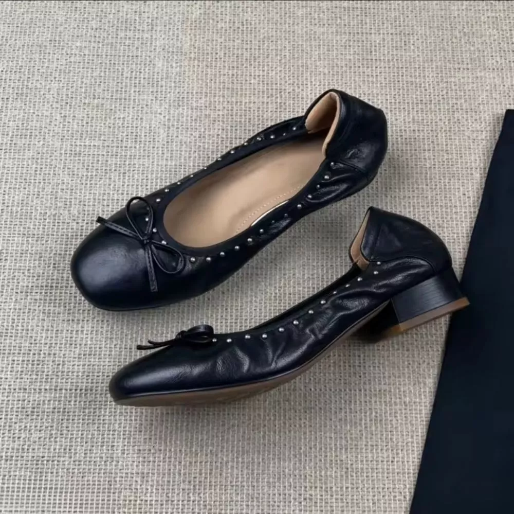 Ballerine nere con fiocchetto e borchie, vista laterale con tacco basso