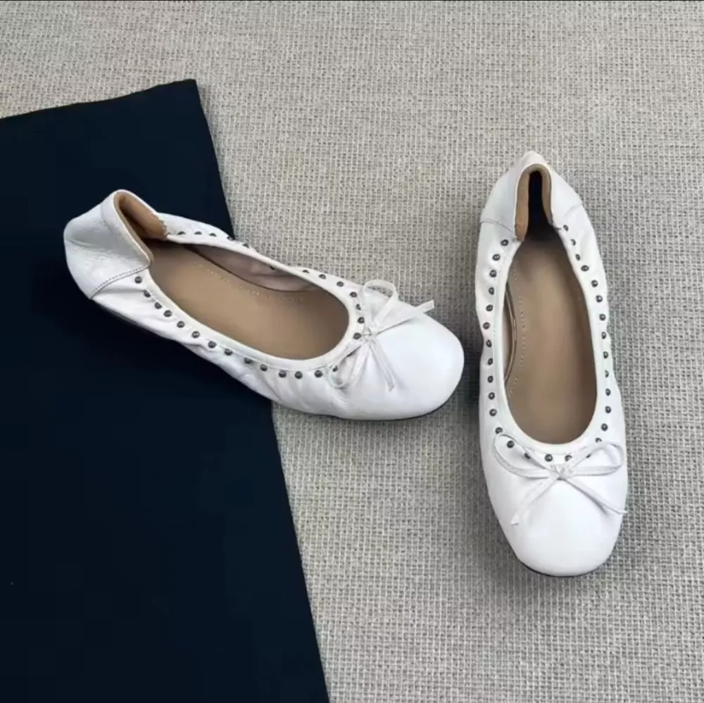 Ballerine bianche con fiocchetto e borchie, viste dall'alto singola coppia
