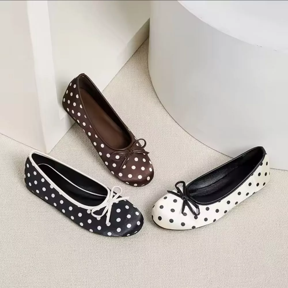 Tre ballerine donna a pois: marrone con pois bianchi, nero con pois bianchi e bianco con pois neri, disposte su pavimento chiaro.
