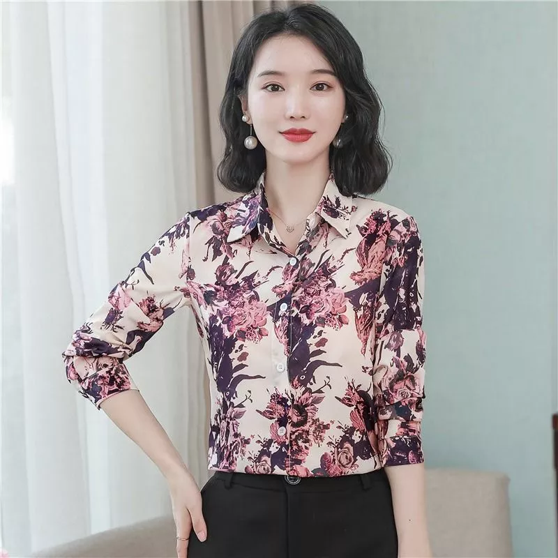 Donna con camicia floreale in posa con mano ai capelli