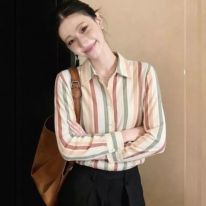 Donna sorride con camicia a righe colorate e orecchini luminosi