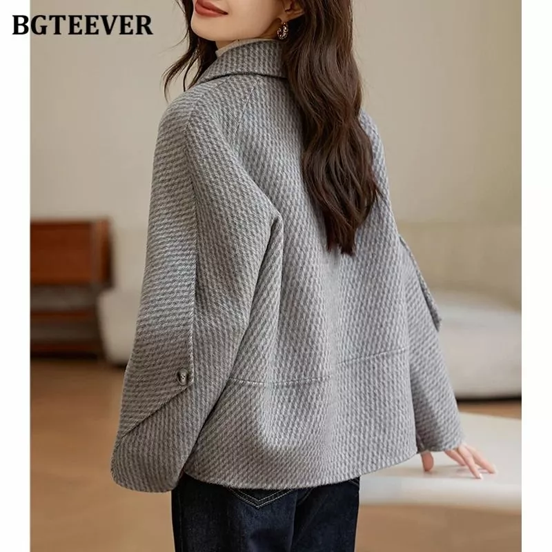 Vista posteriore del cappotto donna grigio indossato dalla modella con capelli castani