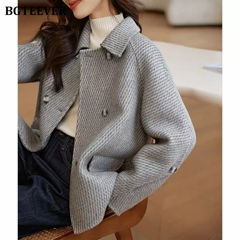 Modella seduta che indossa cappotto donna grigio doppiopetto con dettaglio bottoni alle maniche