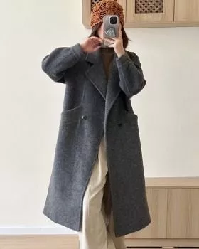 Donna con cappotto grigio lungo mentre si guarda allo specchio