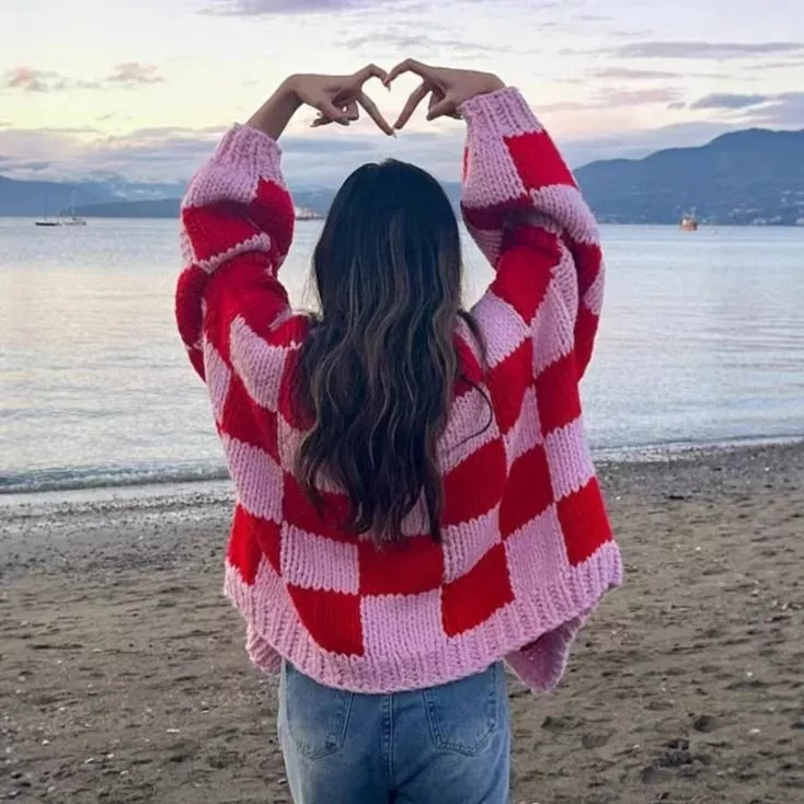 Donna vista da dietro con cardigan a quadri rosa e rosso in spiaggia
