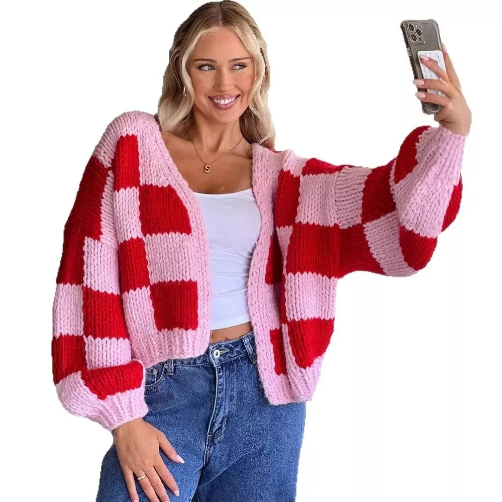 Modella scatta selfie indossando cardigan rosa e rosso a quadri