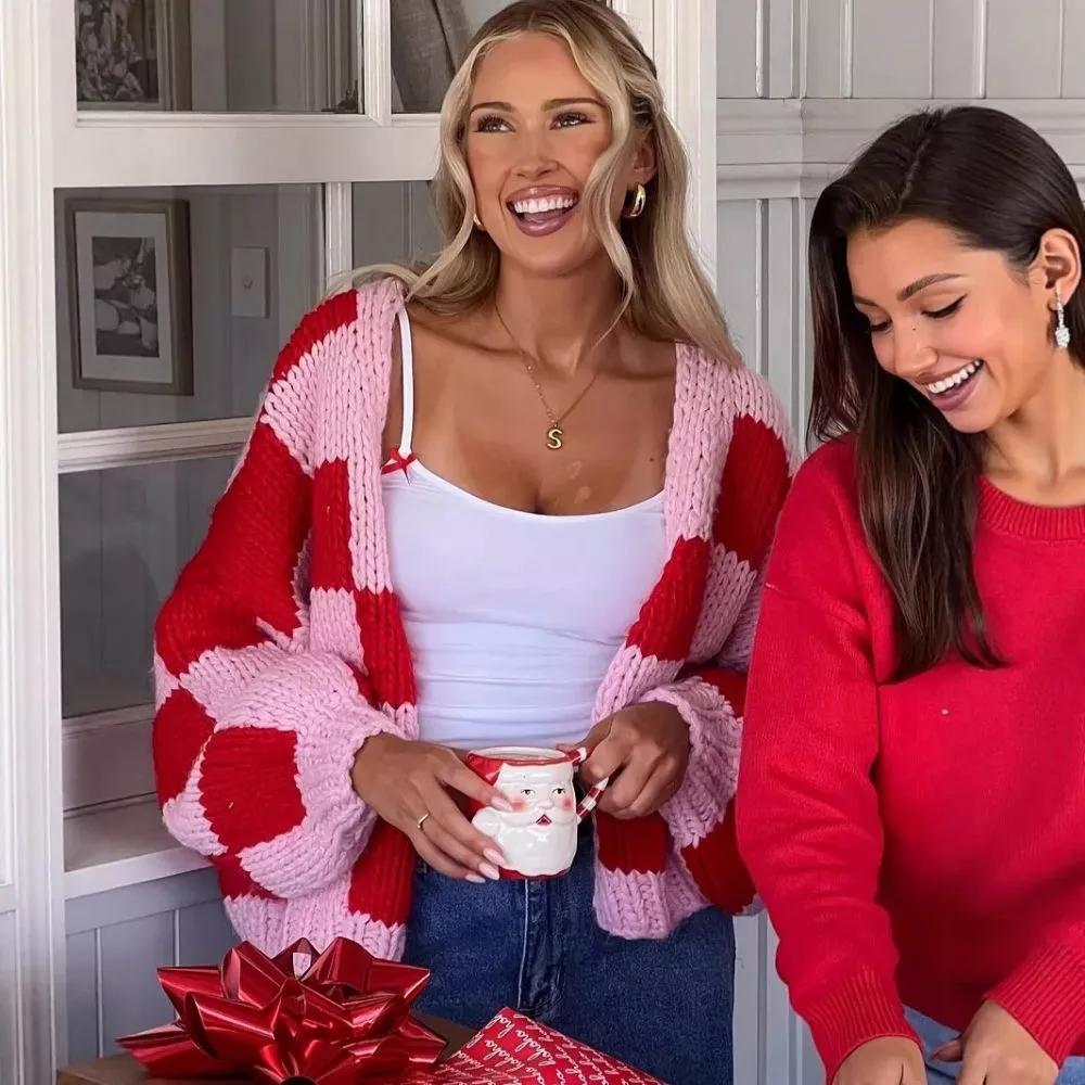 Due donne ridono indossando maglie rosse e cardigan a quadri rosa e rosso