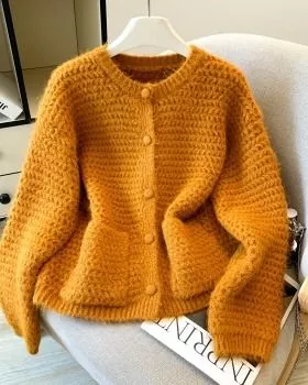 Cardigan giallo donna in maglia lavorata con bottoni rivestiti, su sedia chiara
