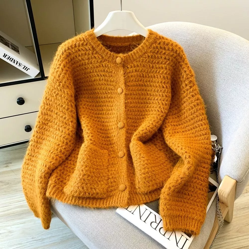 Cardigan giallo donna lavorato a maglia, disteso su sedia
