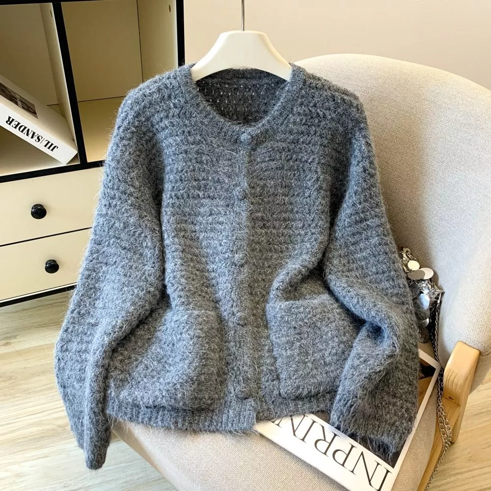Cardigan grigio donna lavorato a maglia, sullo schienale di una poltrona