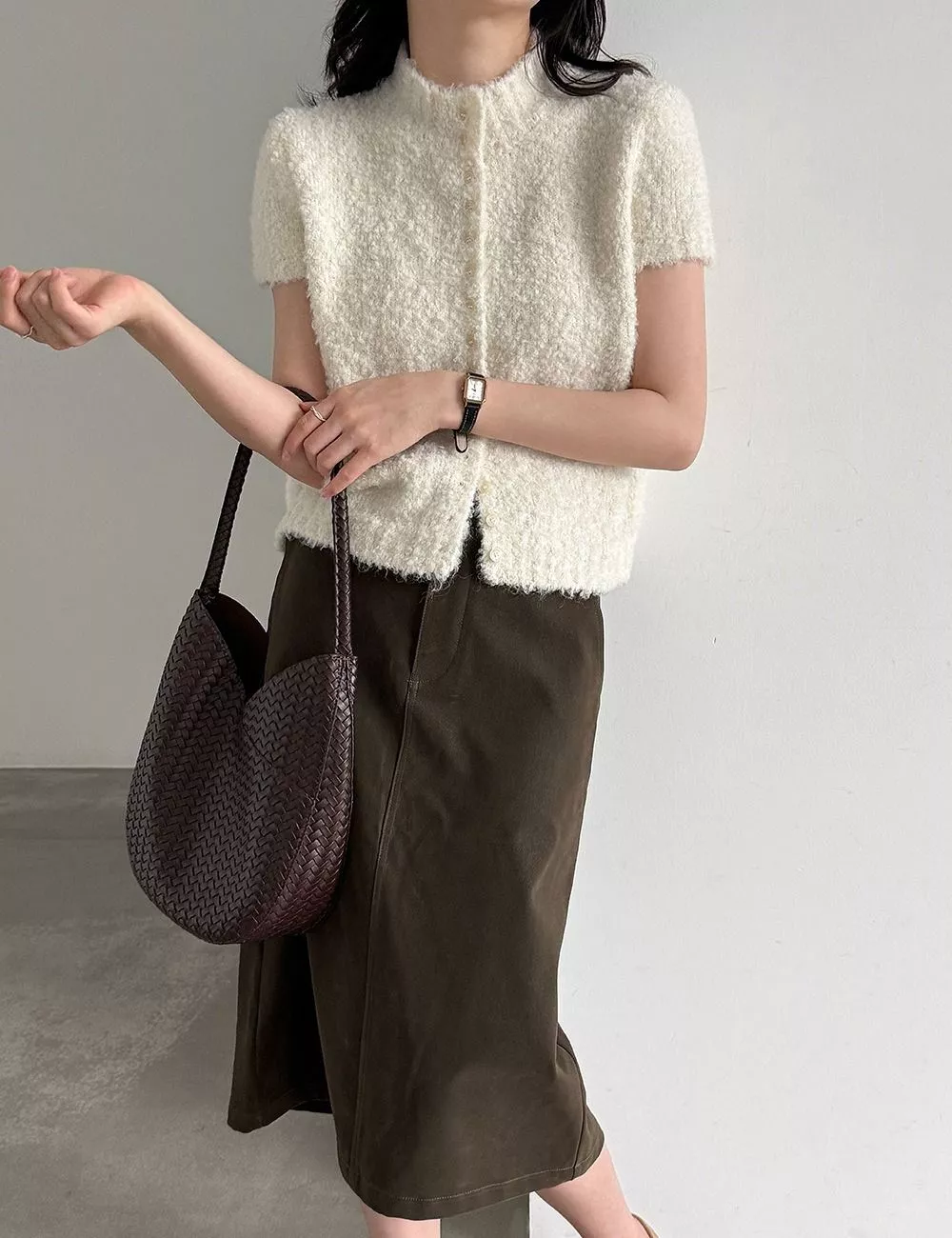 Cardigan grigio e beige piegati su piano con accessori abbinati