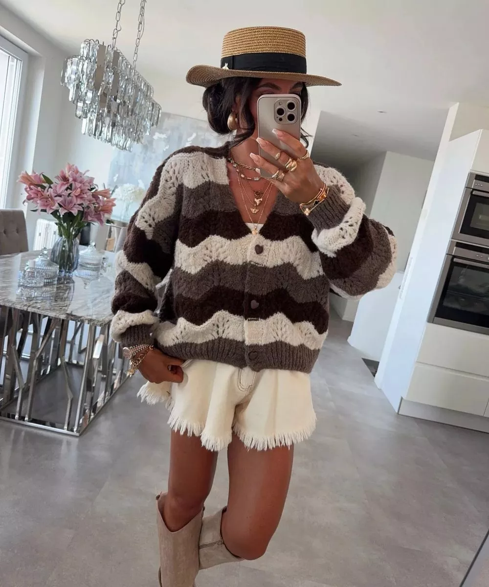 Cardigan marrone a onde indossato con shorts bianchi e cappello a tesa larga