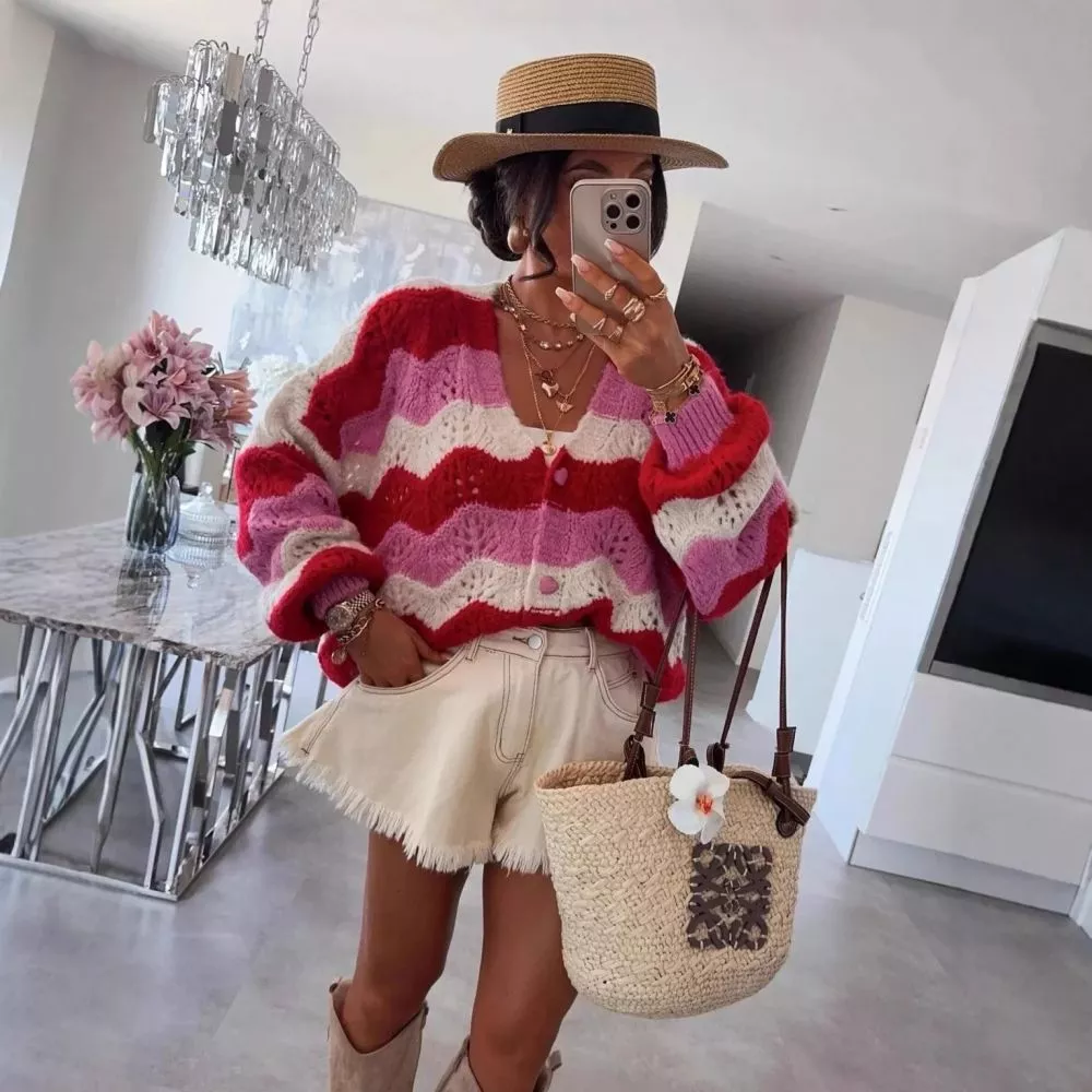Cardigan multicolore con onde rosse, rosa e panna, abbinato a shorts beige e stivali beige