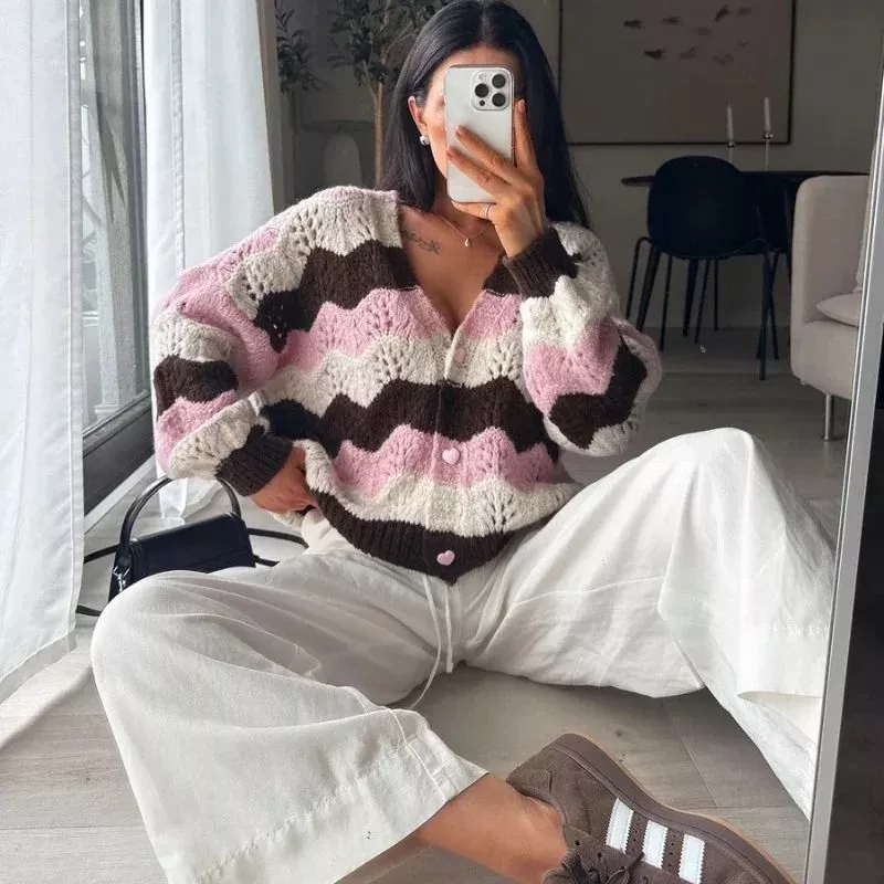 Cardigan multicolore indossato con pantaloni bianchi in posa rilassata