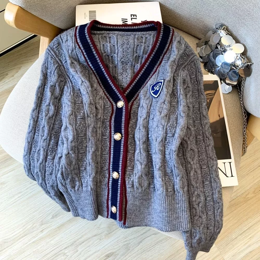 Cardigan donna grigio su poltrona con libro sotto