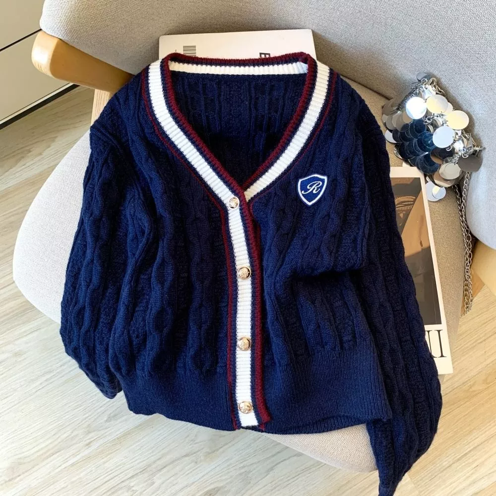 Cardigan donna blu navy con dettagli bianchi e bordeaux su poltrona