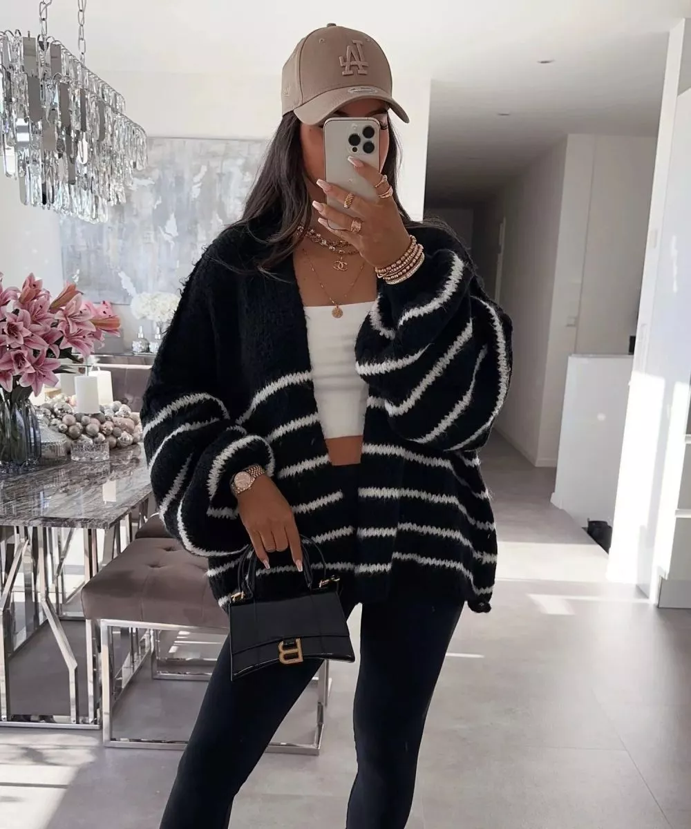 Cardigan donna oversize nero con righe bianche indossato con top bianco e leggings neri