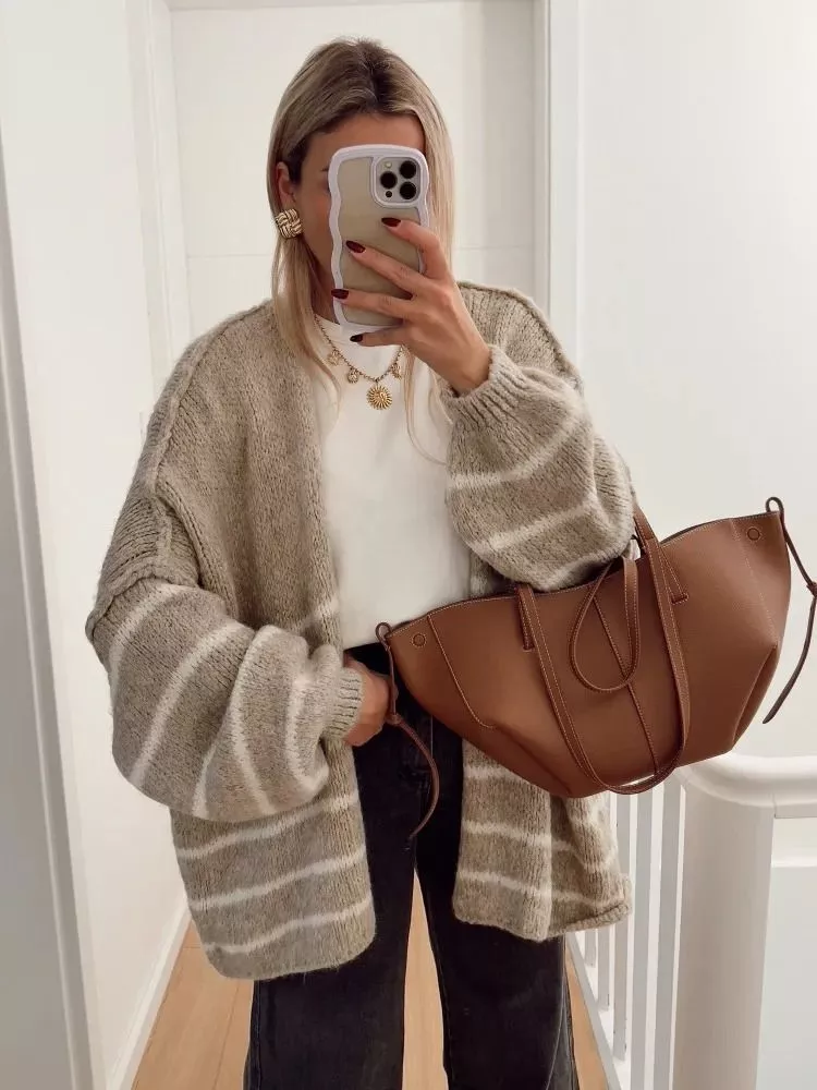 Cardigan donna beige con righe bianche indossato con maglia bianca e jeans scuri
