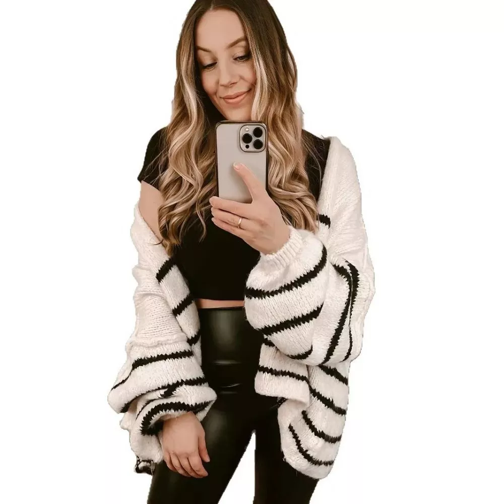 Modella con cardigan bianco e righe nere abbinato a top nero e leggings in pelle