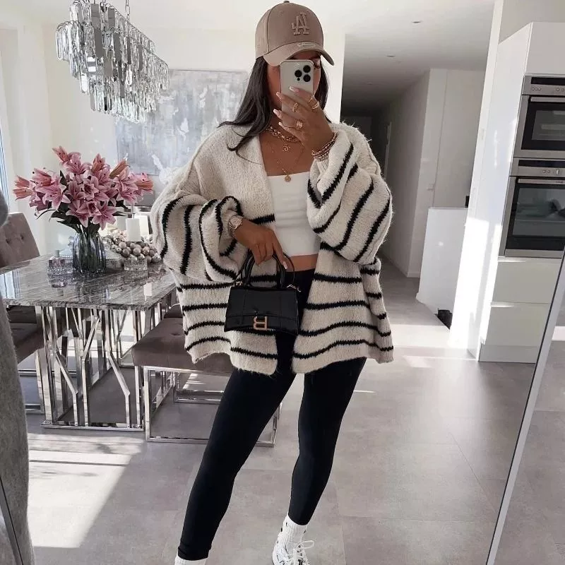 Cardigan bianco con righe nere indossato con accessori oro