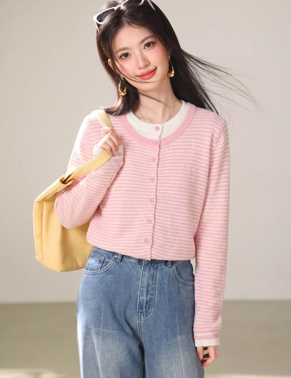 Dettaglio frontale del cardigan rosa a righe indossato con jeans