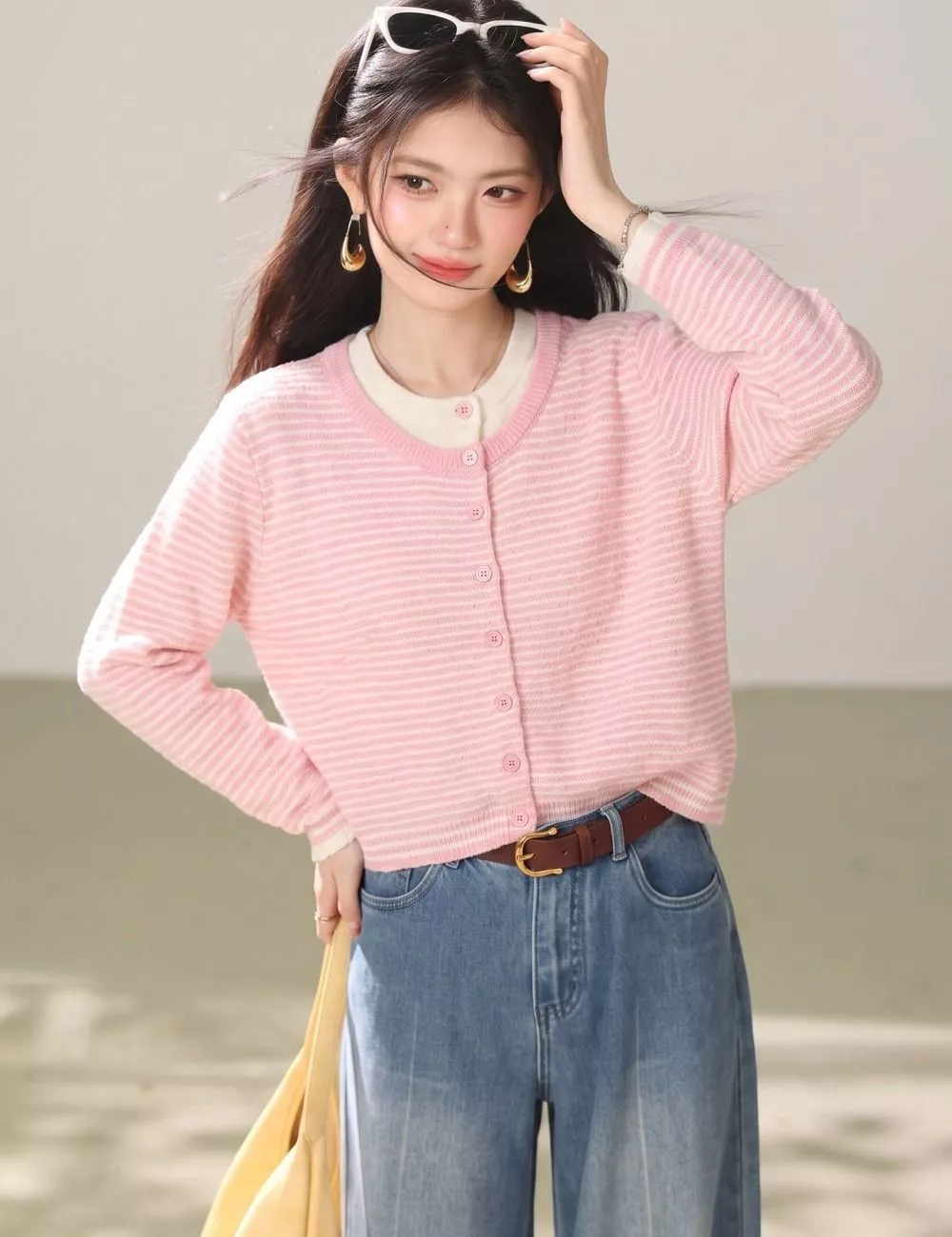Modella con cardigan rosa a righe abbottonato e mano in vita con cintura marrone