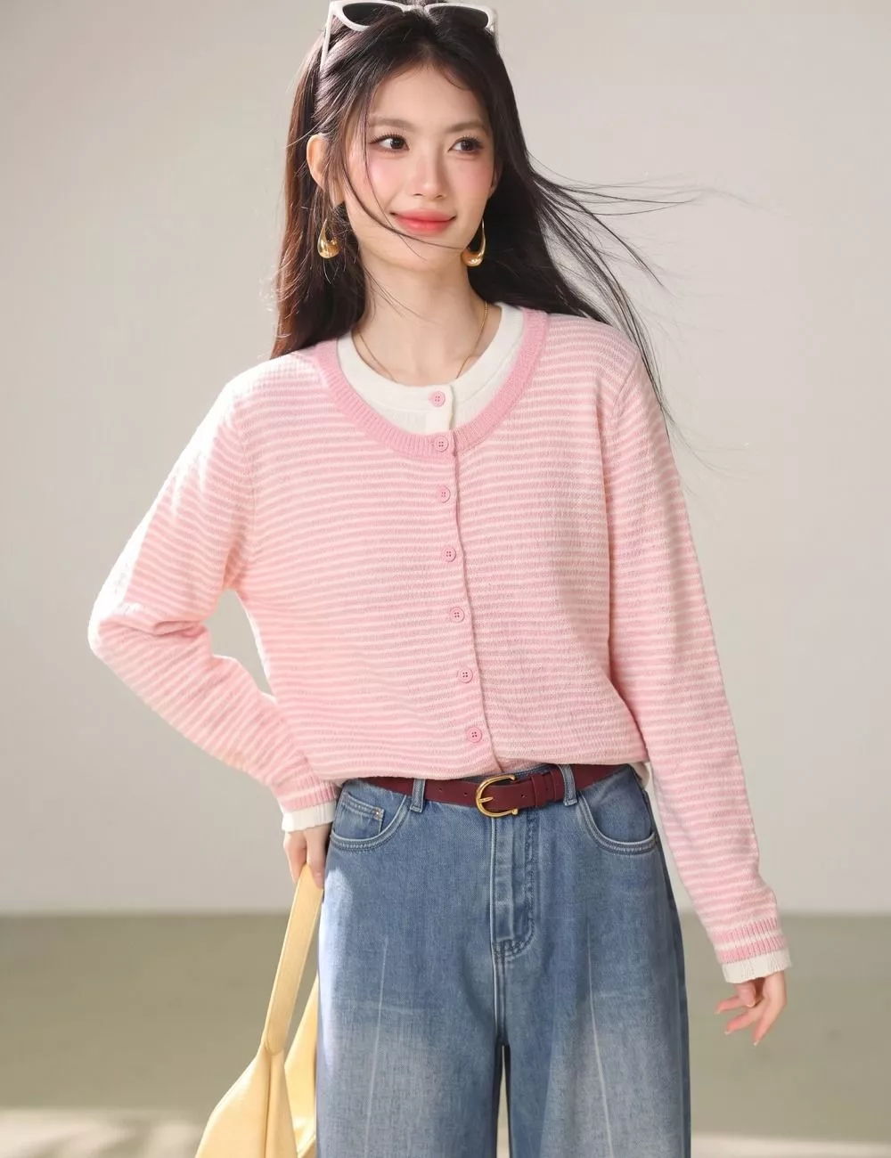 Modella che aggiusta gli occhiali da sole indossando il cardigan rosa a righe