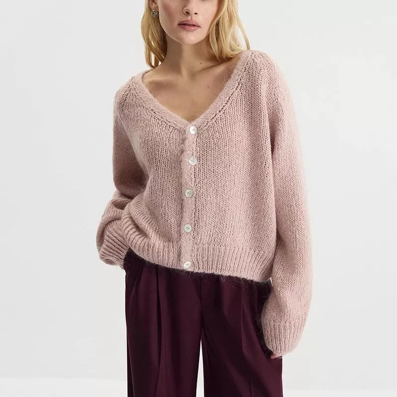 Vista frontale del cardigan rosa cipria da donna, chiuso con bottoni.