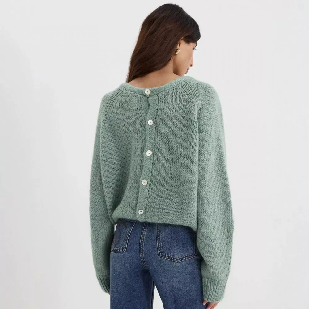 Dettaglio scollo e maniche ampie del cardigan verde donna.