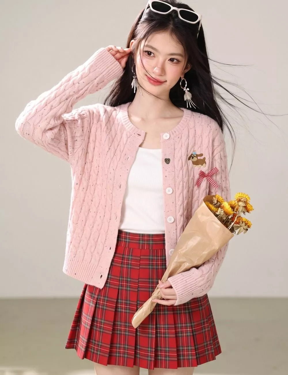 Particolare del cardigan rosa a maglia con piccoli dettagli decorativi sul davanti e chiusura con bottoni