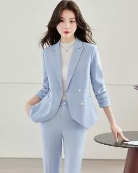 Donna in completo azzurro con giacca doppiopetto e pantaloni abbinati con mani nelle tasche