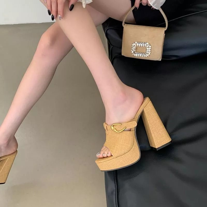 Primo piano scarpe sabot beige su superficie riflettente con sfondo nero e libro