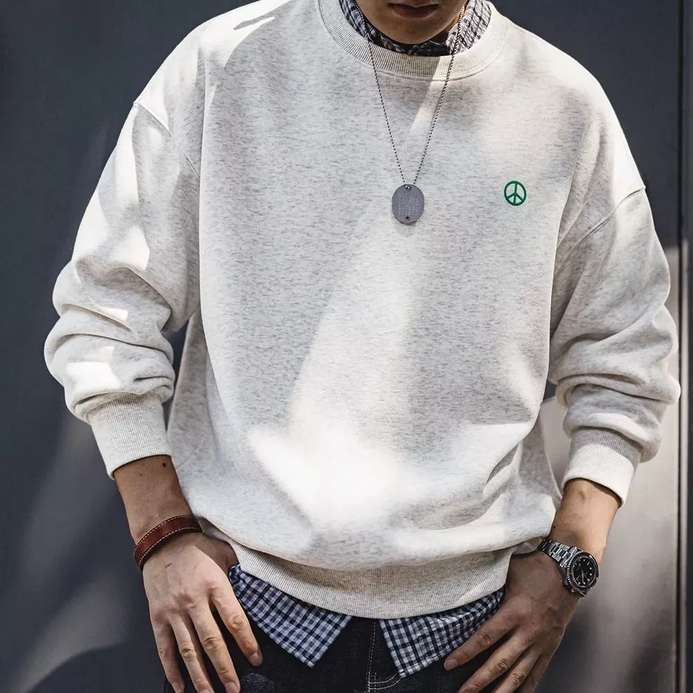 Dettaglio felpa beige uomo con logo verde, vista parte superiore