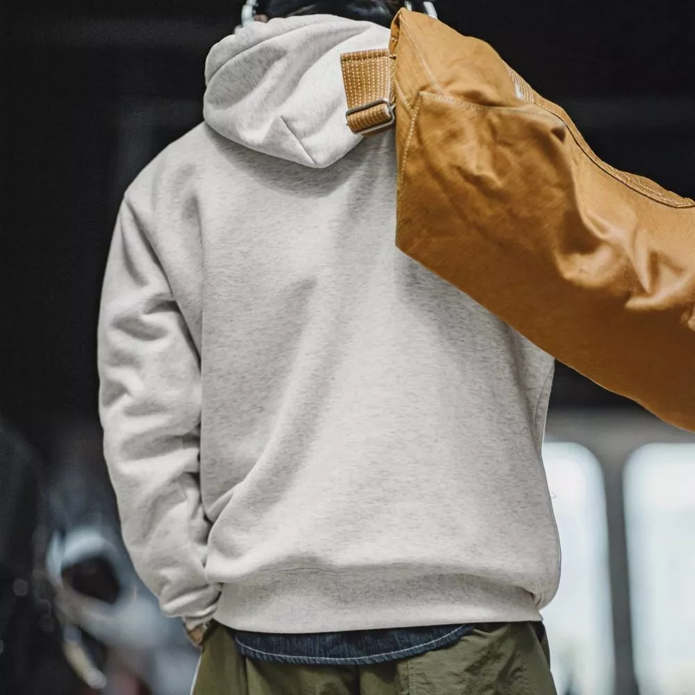 Retro di felpa grigio chiaro con cappuccio indossata da uomo con borsa marrone
