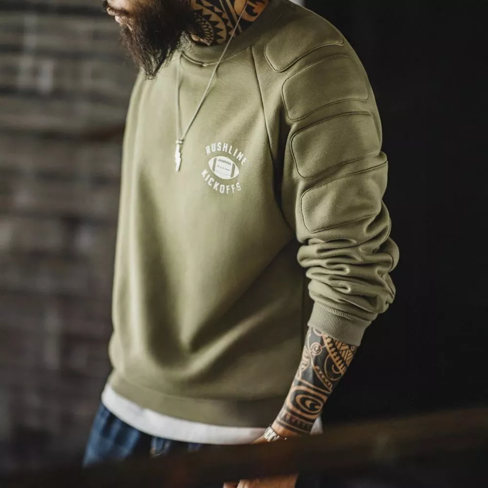 Modello uomo con felpa verde e spalline imbottite vista laterale