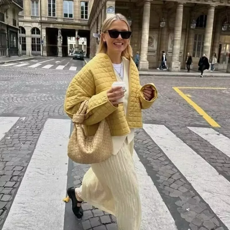 Modella sorridente con giacca trapuntata giallo senape in strada
