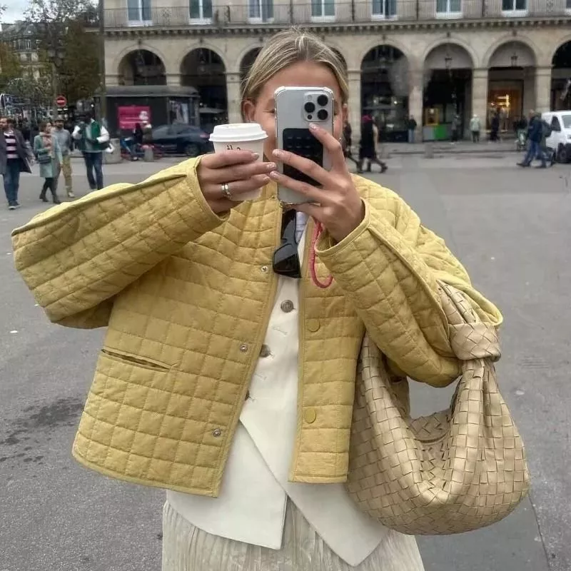 Modella che si scatta un selfie indossando giacca trapuntata giallo senape