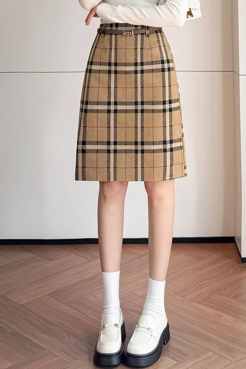Modella con gonna a quadri e maglia bianca, outfit completo