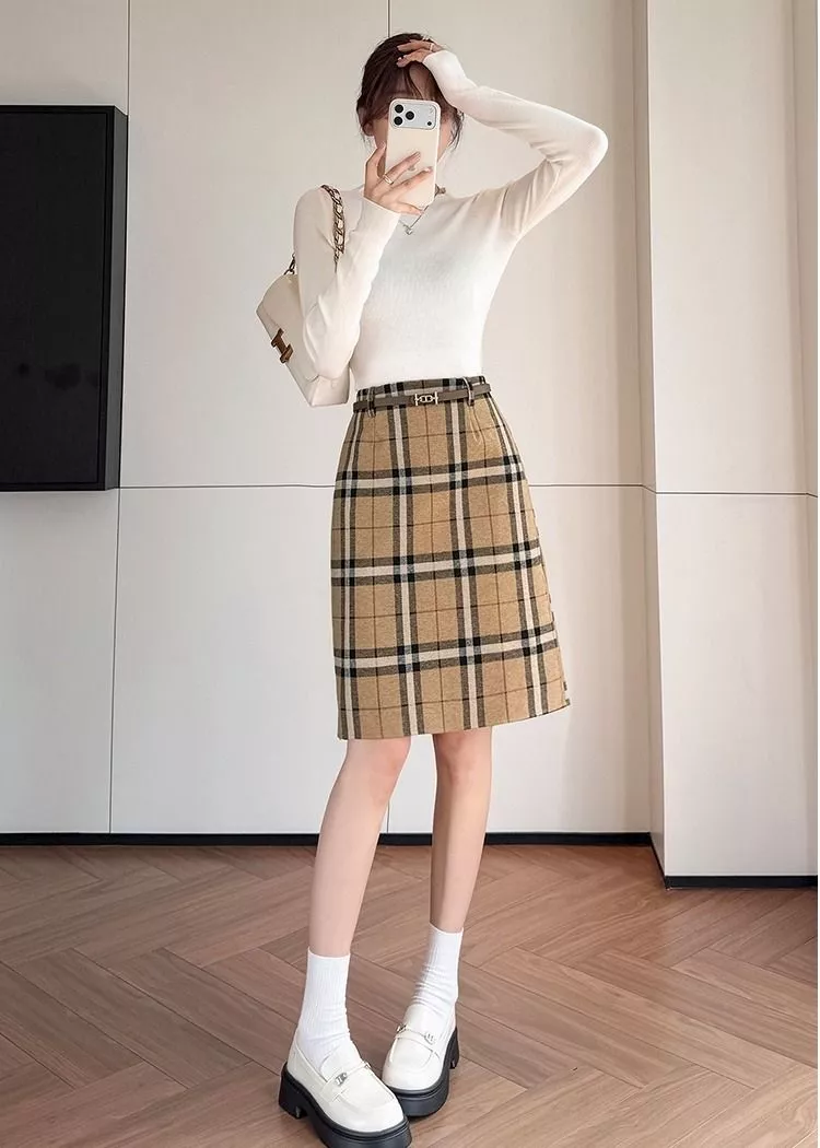 Modella ripresa frontalmente indossando gonna a quadri cachi