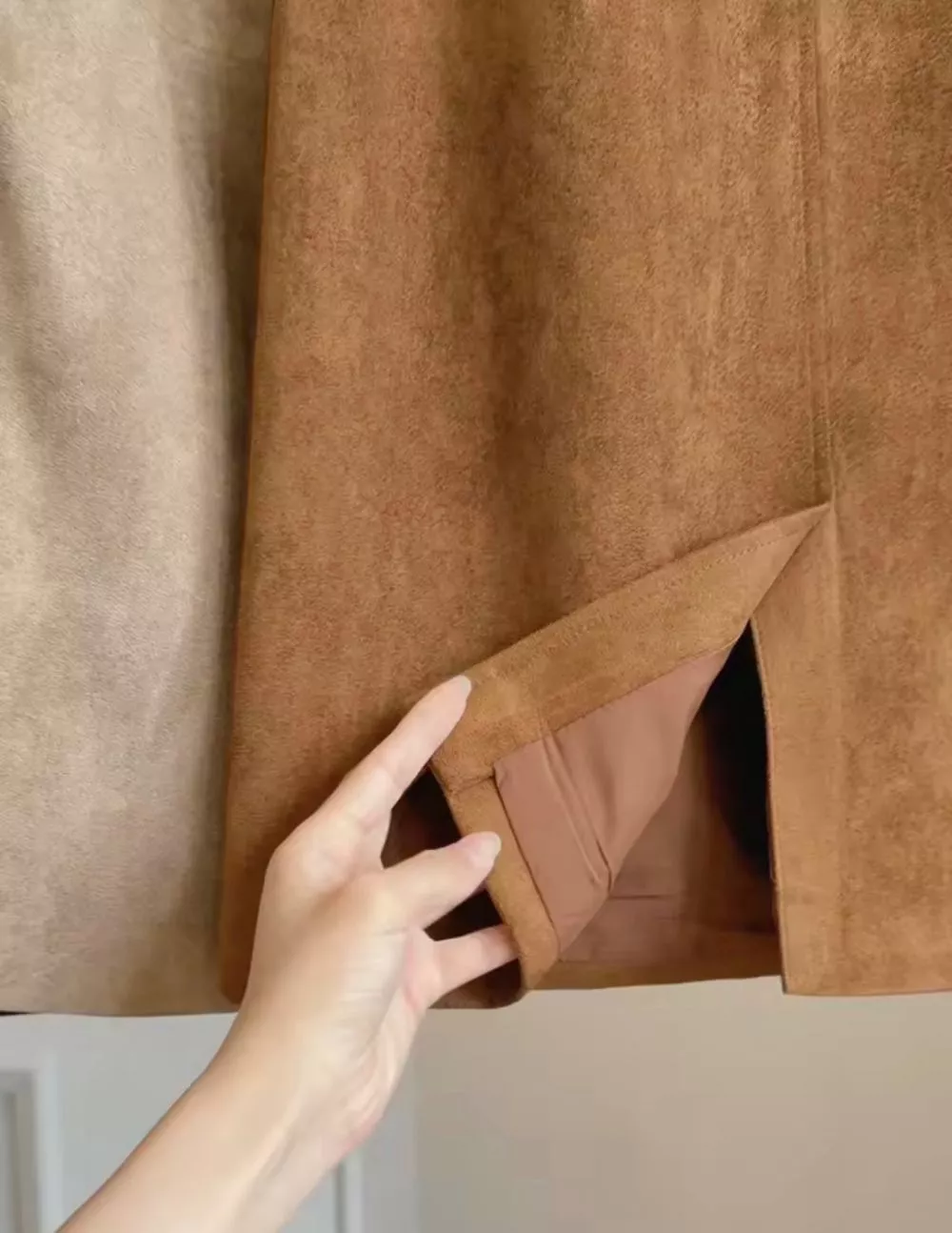 Dettaglio spacco e interno della gonna marrone chiaro con gonna beige chiaro accanto