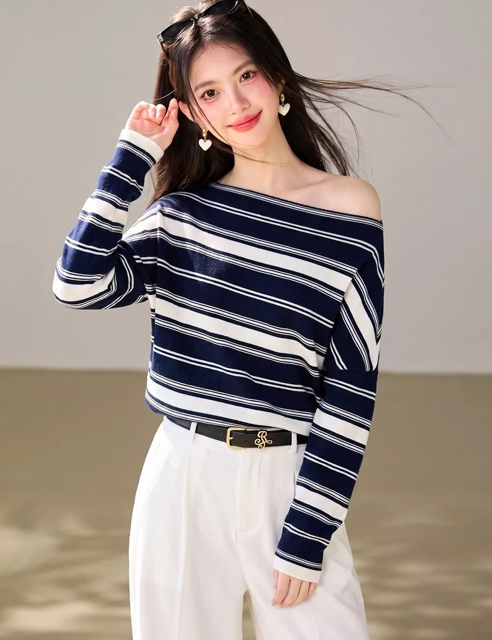 Modello con maglione blu a righe e pantaloni bianchi con cintura nera