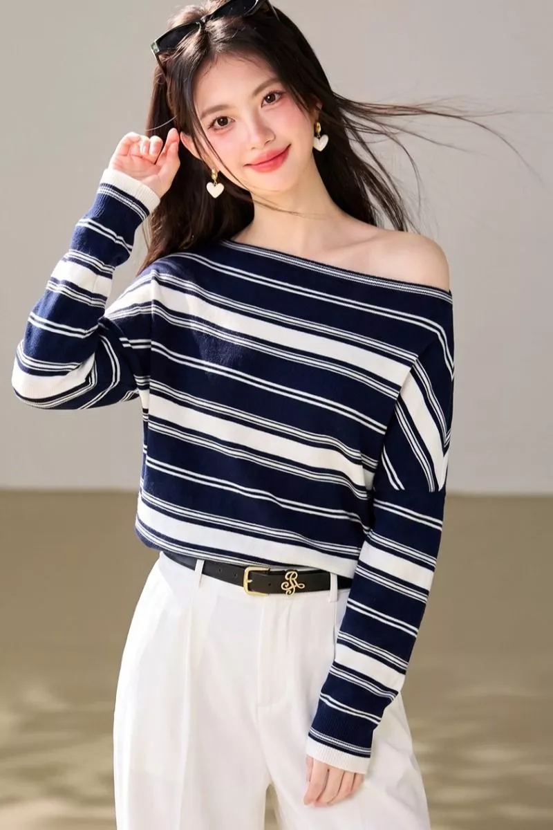Dettaglio della scollatura larga del maglione a righe blu e bianco