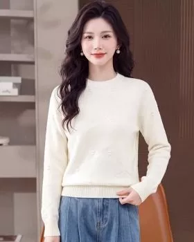 Donna con maglione bianco girocollo a maglia con piccoli pois, abbinata a jeans.