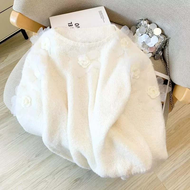 Maglione donna bianco con fiori decorativi bianchi posto su sedia