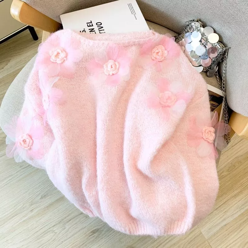 Maglione donna rosa con fiori decorativi rosa posto su sedia