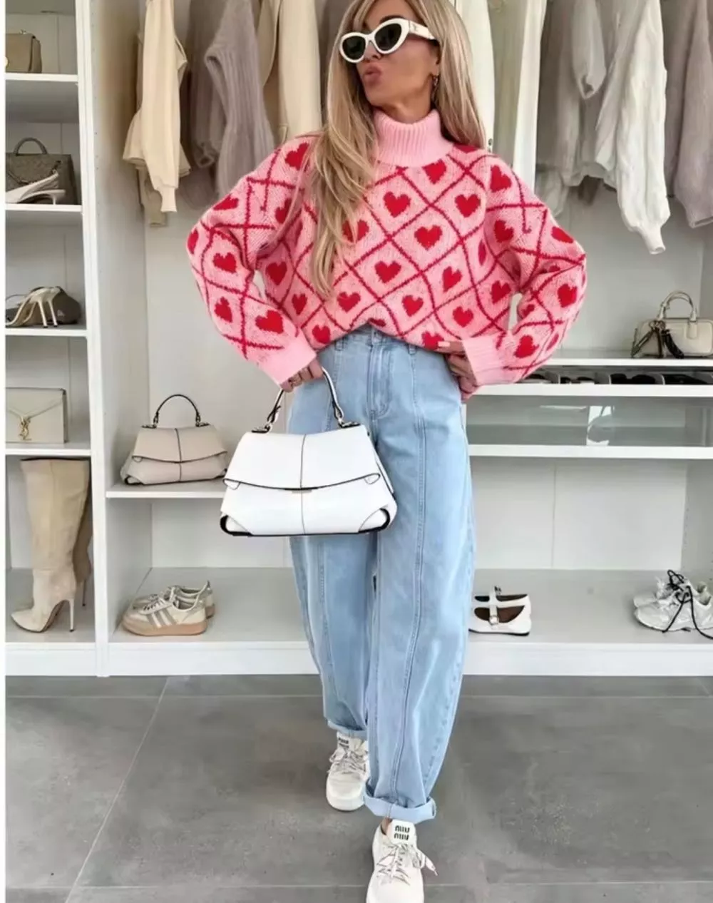 Maglione donna rosa con motivo a cuori rossi indossato frontalmente con jeans chiari e occhiali bianchi